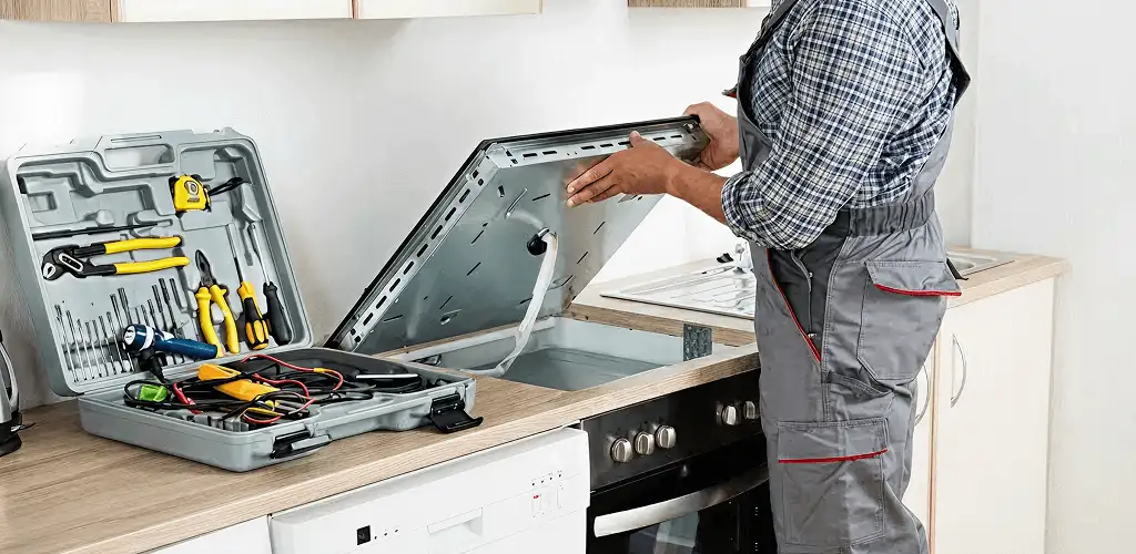Handyman repairing a cooktop and checking wiring connections in Colorado Springs, CO