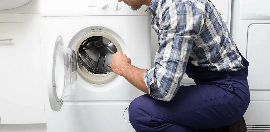 Handyman inspecting a dryer drum and internal parts for repair in Colorado Springs, CO