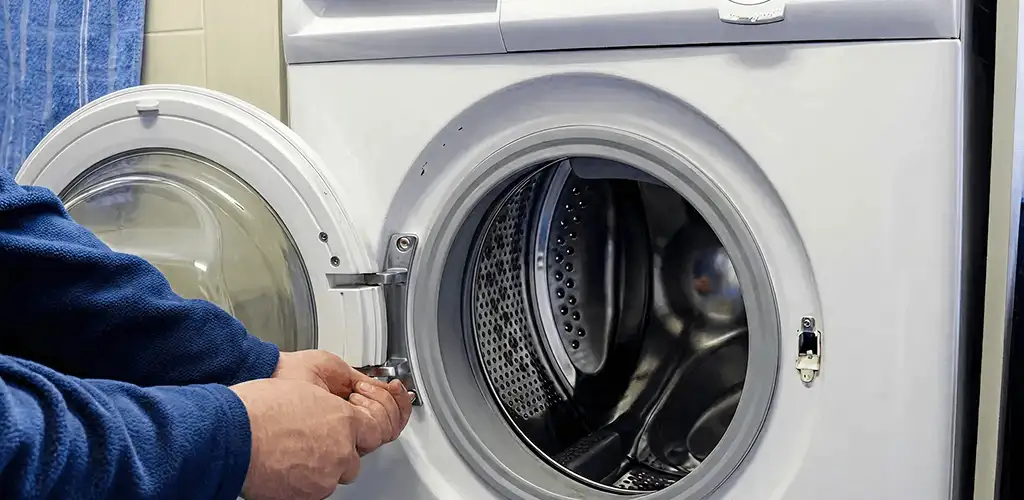 Washing machine repair handyman checking a front-load washer door and latch in Colorado Springs, CO