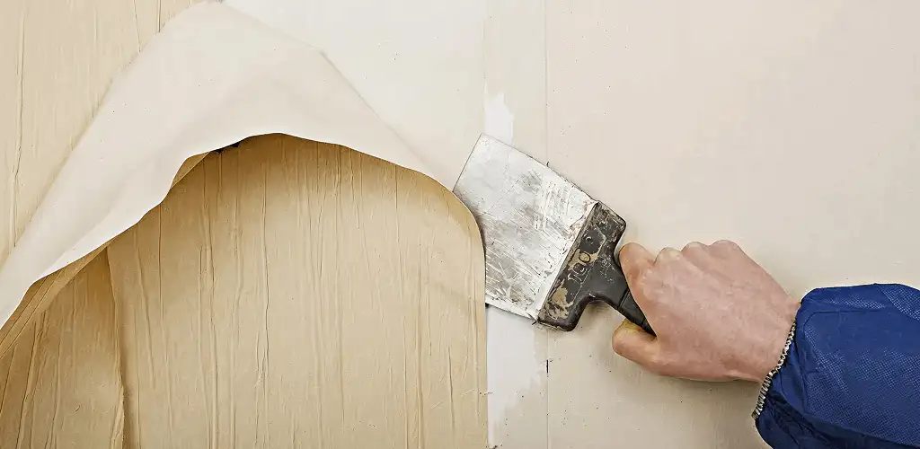 Handyman removing wallpaper with a scraper for wall preparation in Colorado Springs, CO