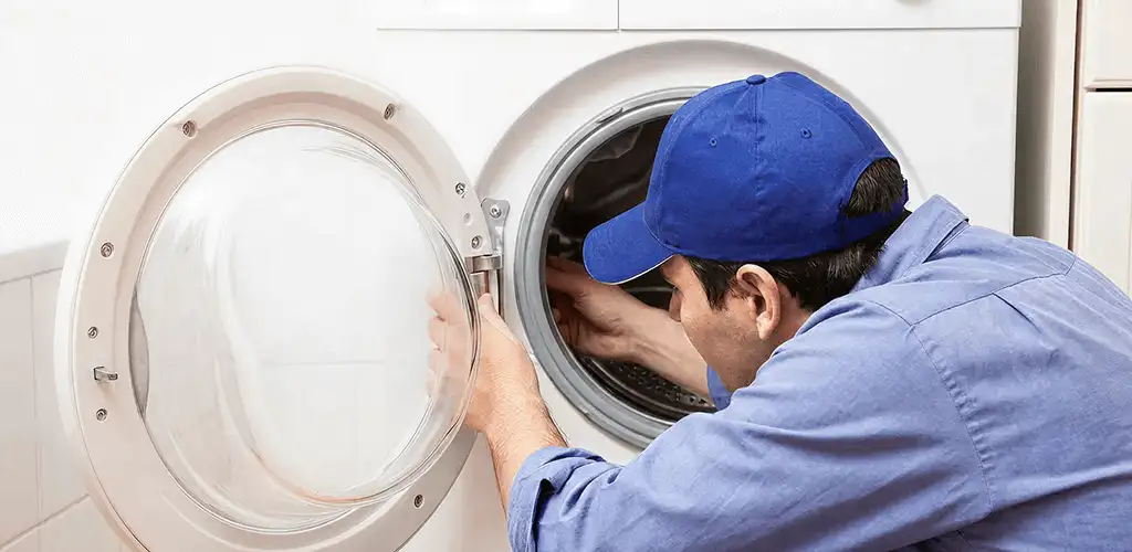 Washing machine repair handyman inspecting a front-load washer drum in Colorado Springs, CO
