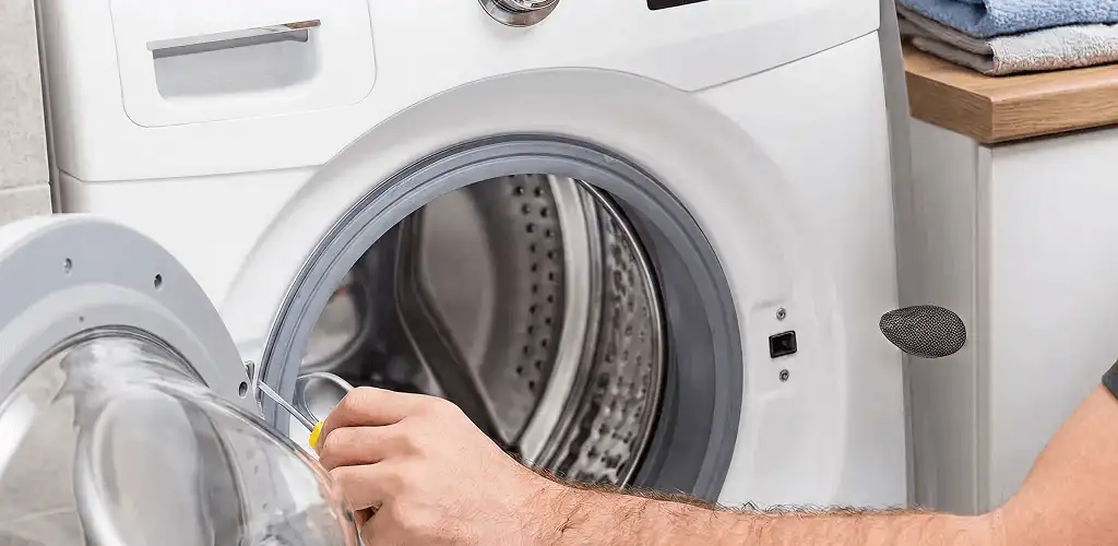 Handyman repairing a front-load washing machine and inspecting the drum in Colorado Springs, CO