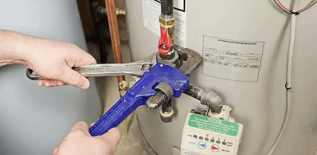 Water heater repair technician tightening the shutoff valve and supply line in Colorado Springs, CO